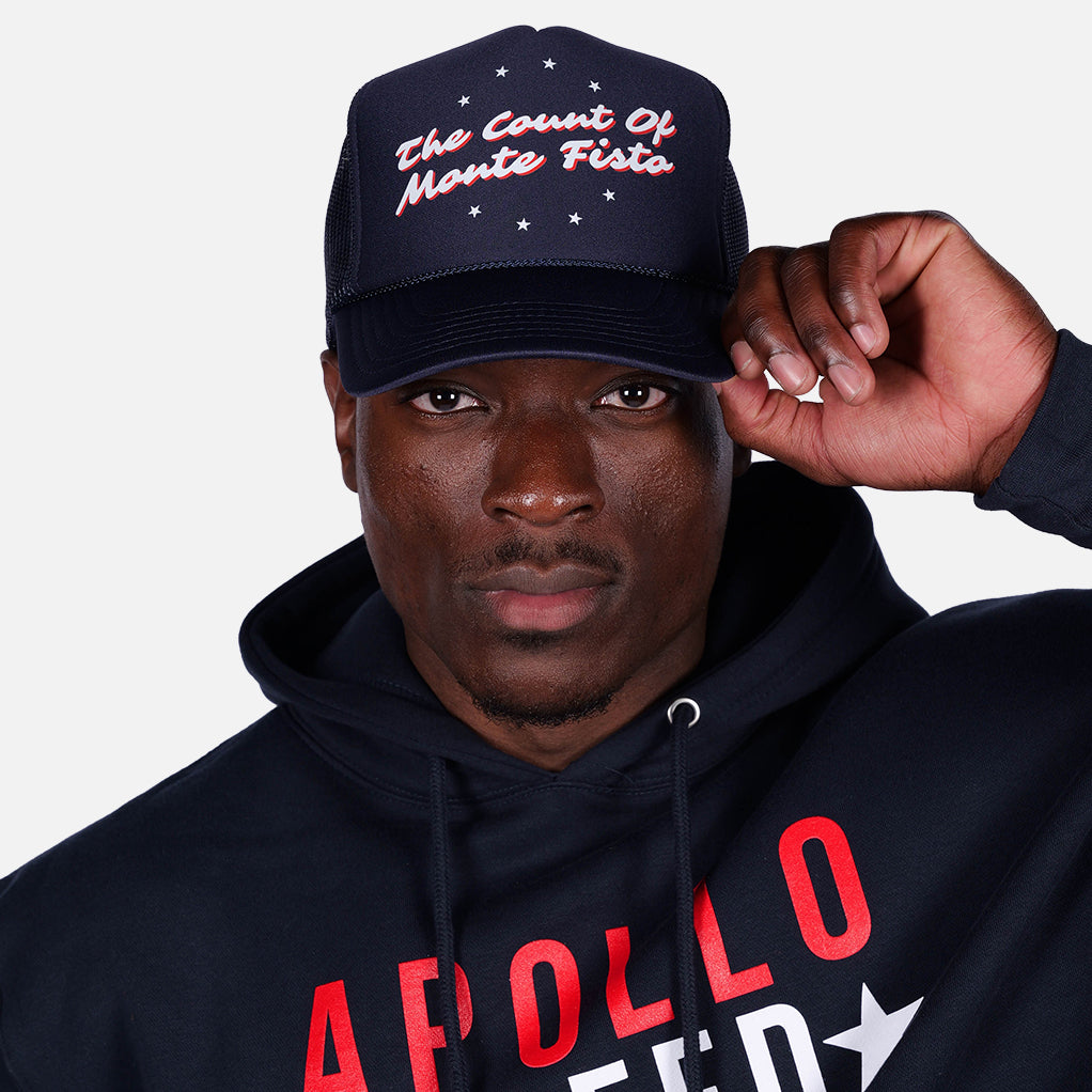 Man wearing a black cap and hoodie with text, against a plain background